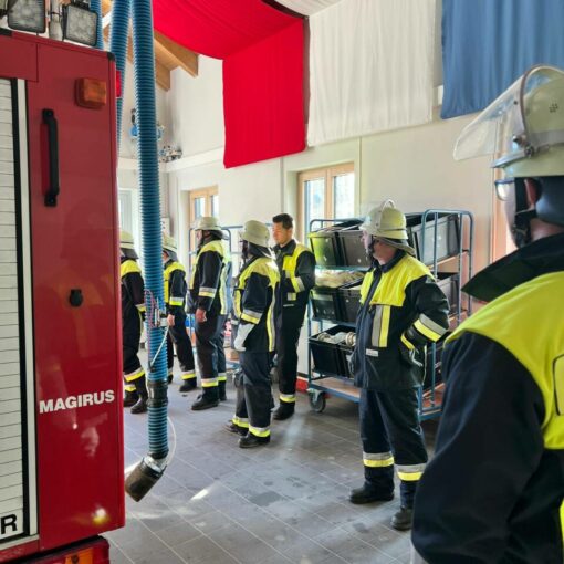 Die Feuerwehrmänner und -frauen stehen im Gerätehaus und warten auf die Übung.